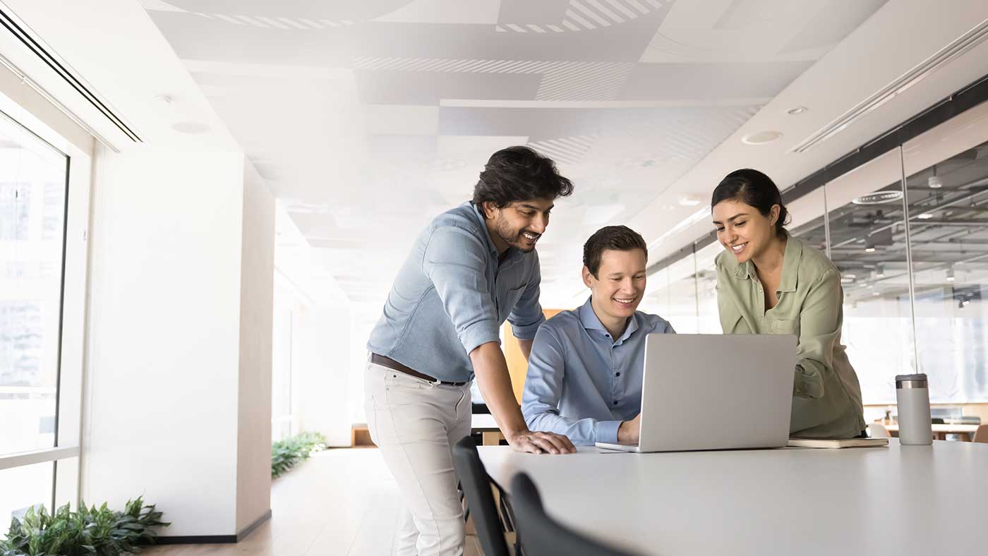 people at office standing around a laptop
